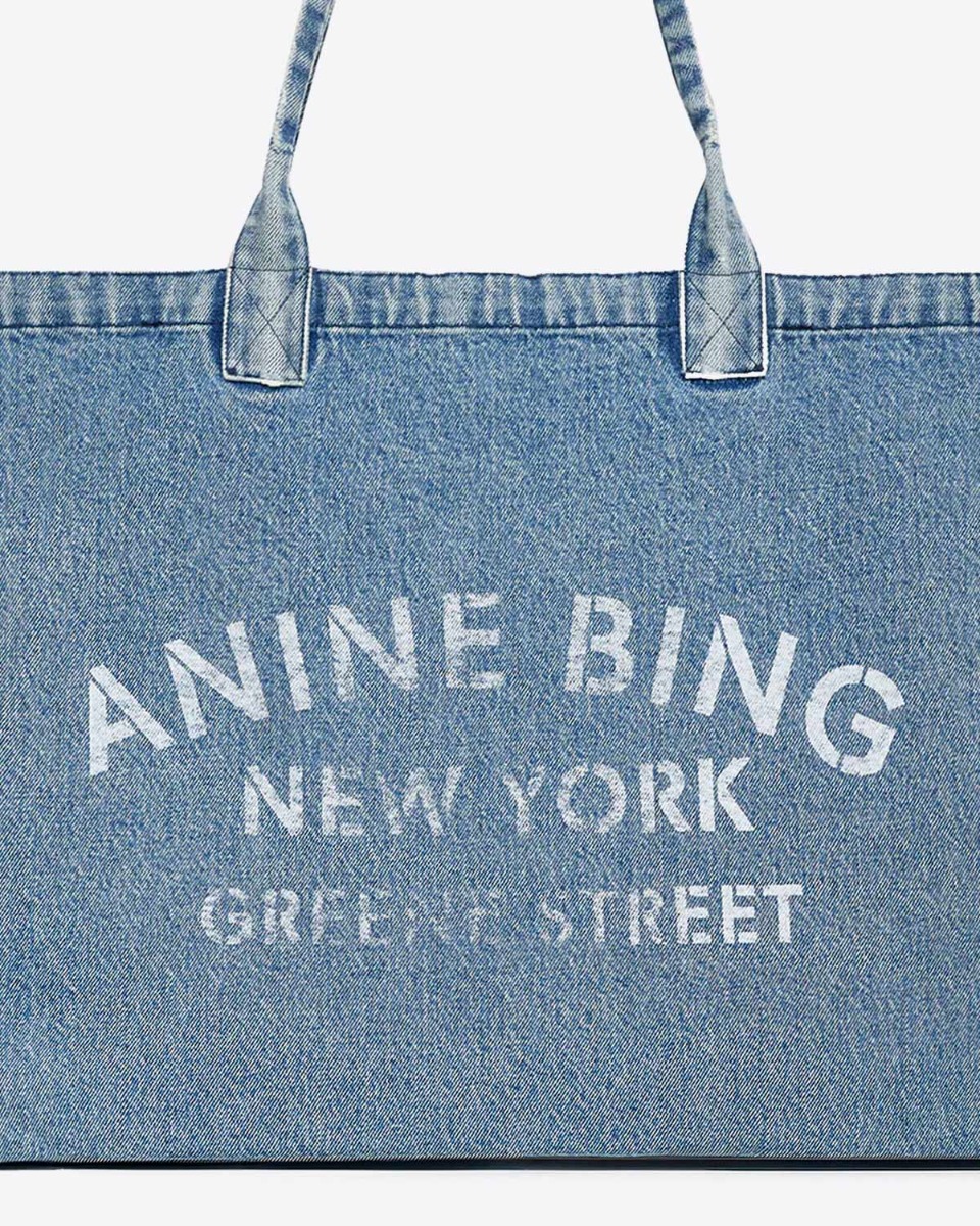Cabas Leo Denim Tote Anine Bing en toile de coton bleu délavé. Détail de la sérigraphie blanche ANINE BING NEW YORK GREENE STREET.