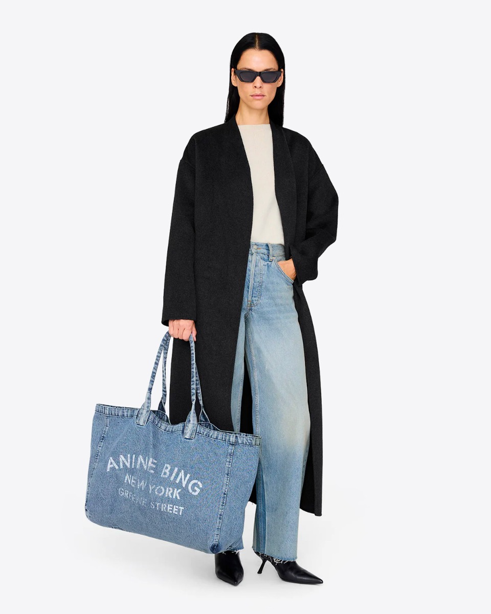 Cabas Leo Denim Tote Anine Bing en toile de coton bleu délavé, porté à la main.