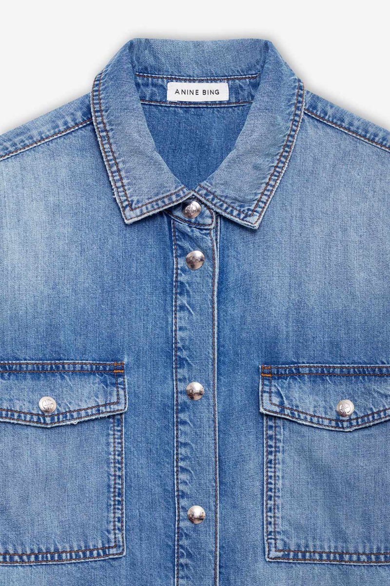 Chemise en jean Paxton Anine Bing en coton bleu d&eacute;lavage Tidal. D&eacute;tail des boutons-pression en m&eacute;tal argent&eacute; logo AB. 