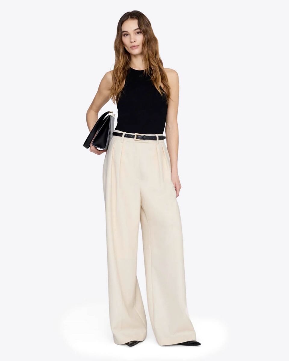 D&eacute;bardeur emmanchures am&eacute;ricaines Cole Anine Bing en maille c&ocirc;tel&eacute;e noire, port&eacute; de face avec un pantalon large beige clair.