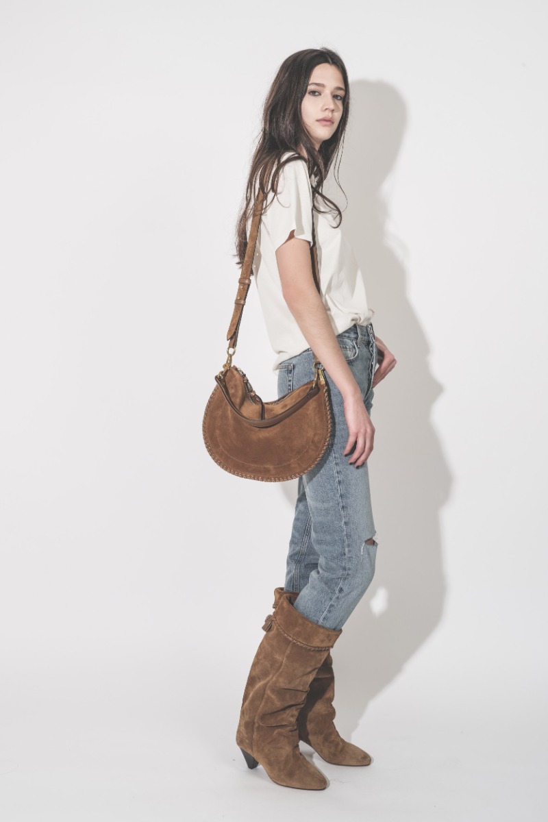 Jean taille haute slim Bruno Anine Bing en denim r&eacute;g&eacute;n&eacute;ratif bleu d&eacute;chir&eacute; aux genoux, port&eacute; avec un sac et des bottes Isabel Marant.