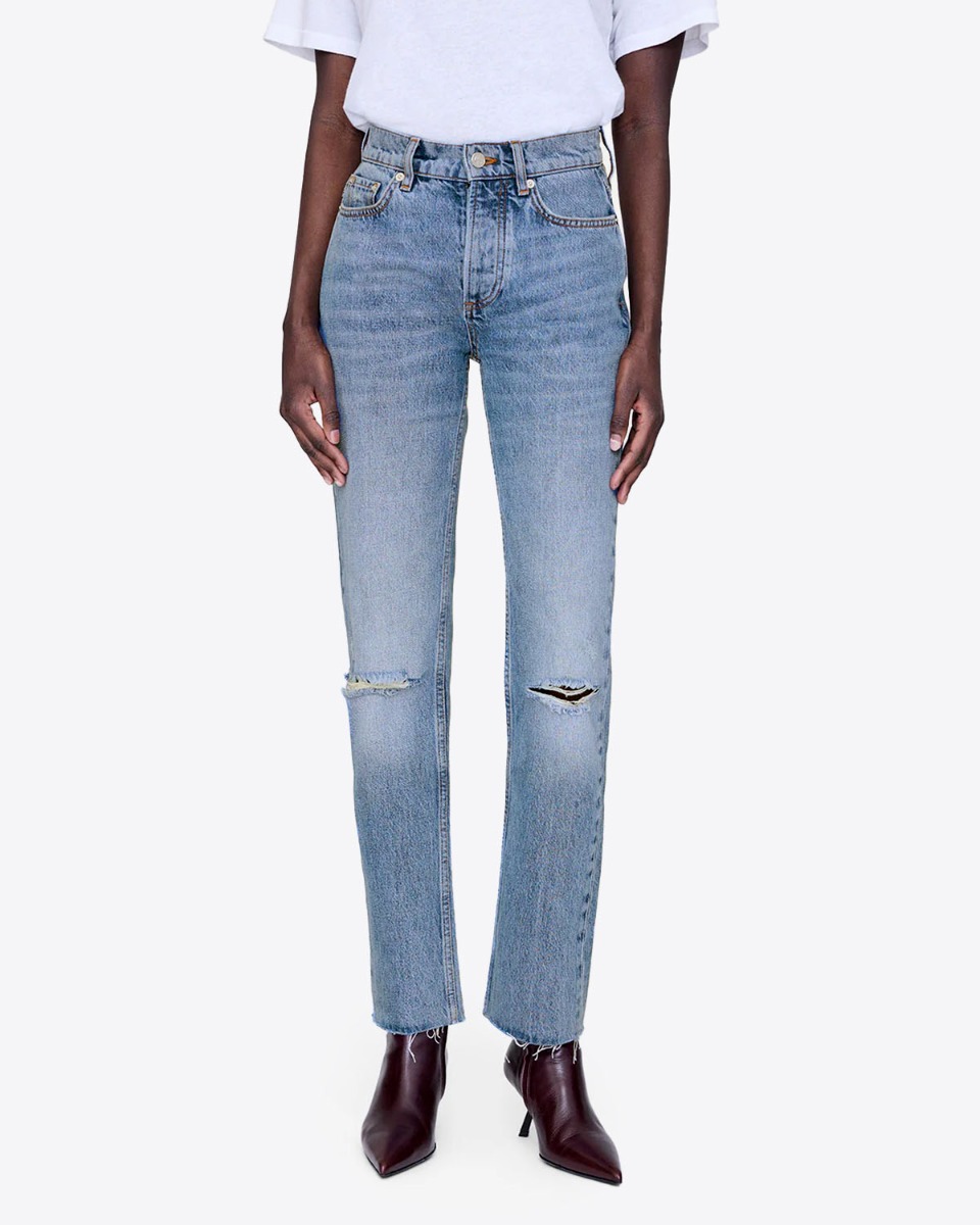 Jean taille haute slim Bruno Anine Bing en denim régénératif bleu déchiré aux genoux et porté de face avec des chaussures pointues.