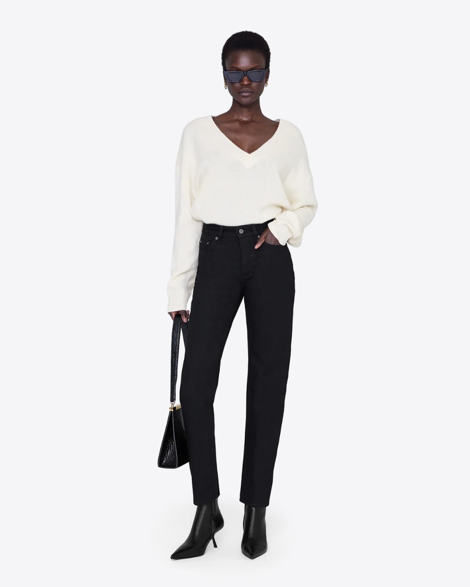 Jeans taille haute Bruno Anine Bing en toile noire, porté de face avec un pull en cachemire écru.