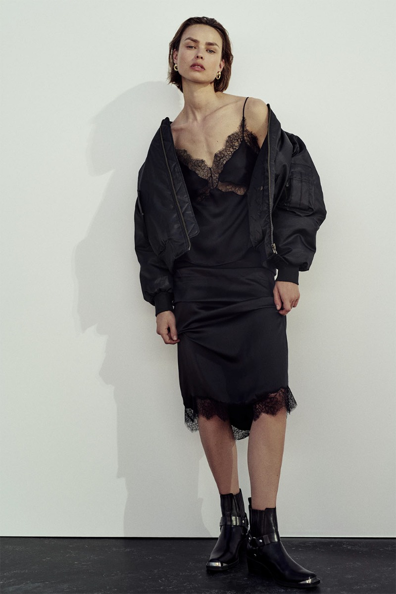 Jupe longue Shelby noire Anine Bing en satin et dentelle esprit lingerie portée avec un bombardier noir.