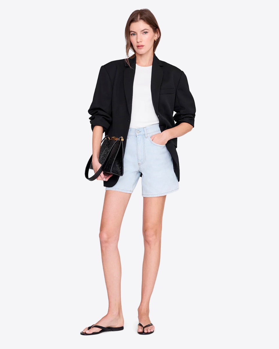 Short Delaney Anine Bing en denim bleu clair d&eacute;lavage &laquo; Lucid Blue &raquo;, port&eacute; avec une veste noire.