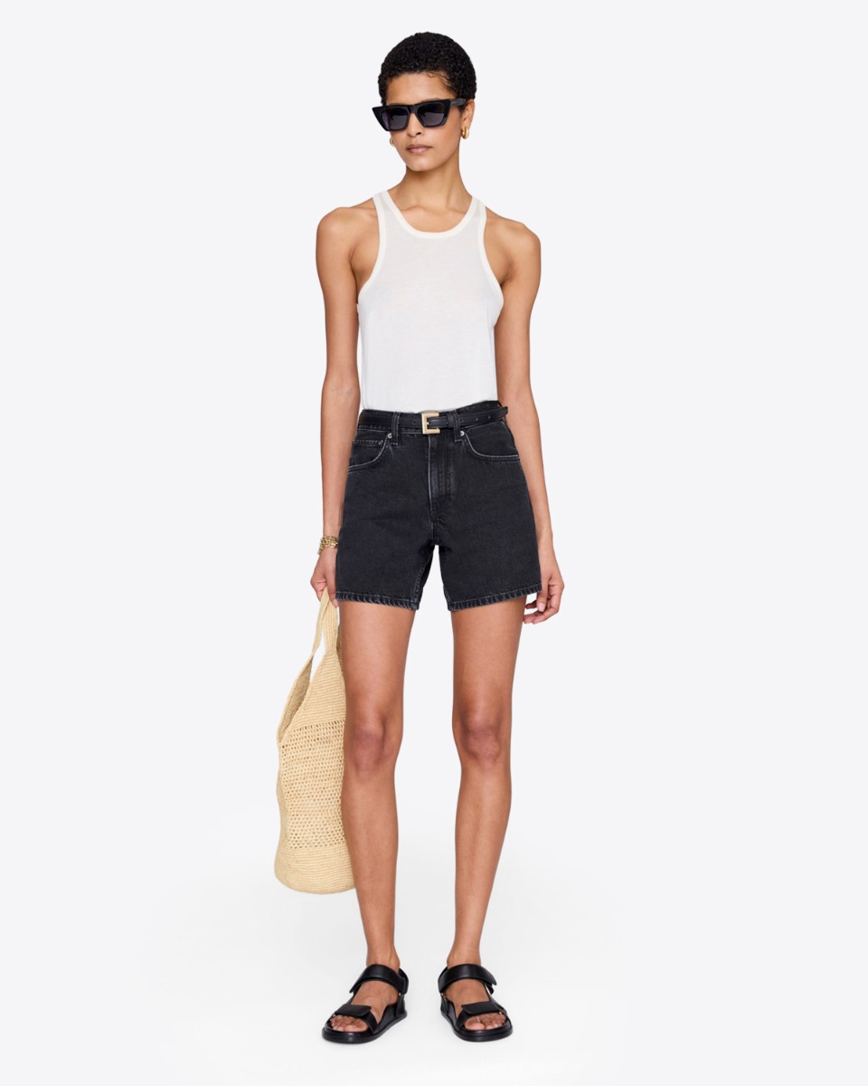 Short Delaney Anine Bing en denim noir d&eacute;lav&eacute;, port&eacute; de face avec un d&eacute;bardeur blanc.