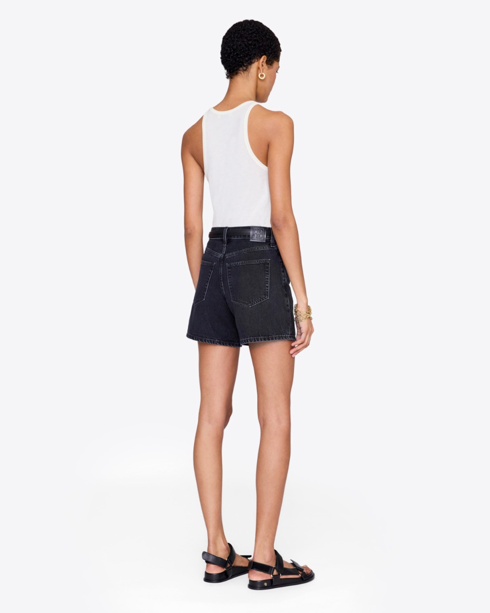 Short Delaney Anine Bing en denim noir d&eacute;lav&eacute;, port&eacute; de dos avec un d&eacute;bardeur blanc.
