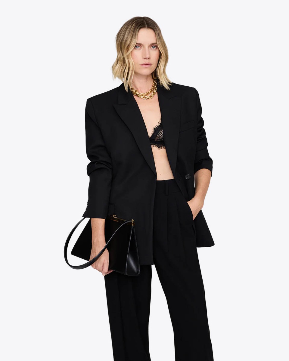 Soutien-gorge triangle en dentelle noire Anine Bing, port&eacute; sous une veste noire.