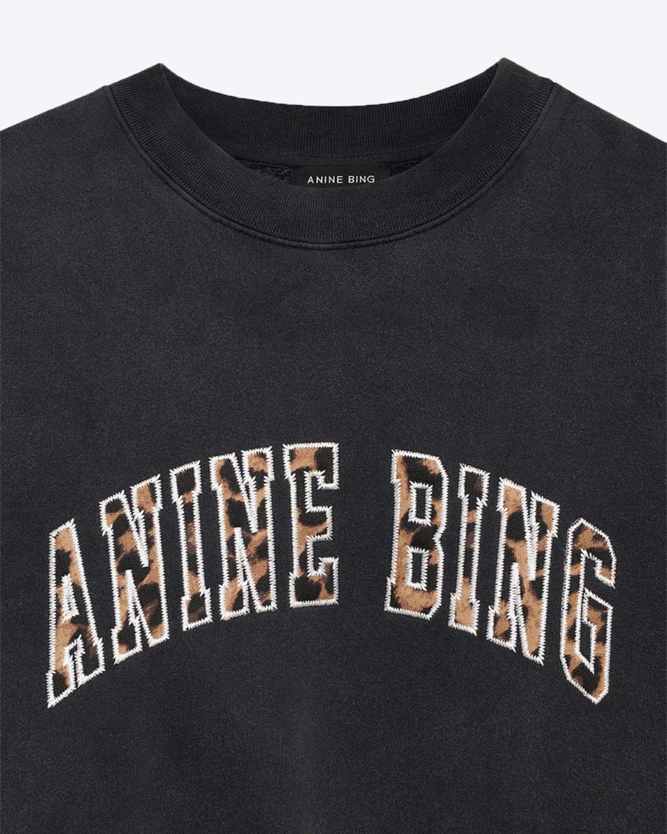 Sweat-shirt Miles Anine Bing en coton noir d&eacute;lav&eacute;, logo l&eacute;opard. D&eacute;tail du logo l&eacute;opard d&rsquo;&laquo; Anine Bing &raquo; sur le devant.