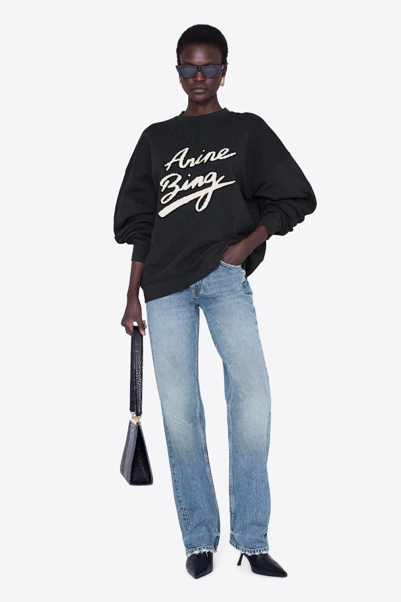 Produit Sweat-shirt Miles Anine bing noir, logo chenille écru, signature, porté avec un jean bleu ciel.
