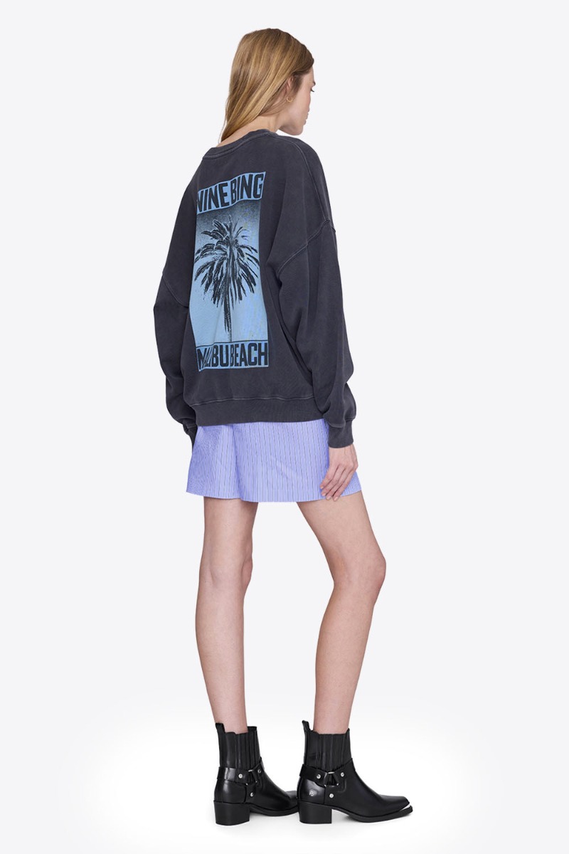 Sweatshirt Miles Palm Anine Bing en coton noir délavé sérigraphier palmier bleu dans le dos, logo « ANINE BING » sur le poitrine porté de dos.