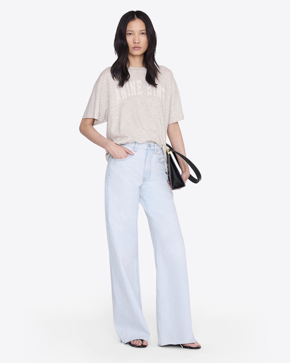 T-shirt Cade Anine Bing en coton l&eacute;opard cr&egrave;me logo blanc &laquo; ANINE BING &raquo; devant, port&eacute; de face avec le devant rentr&eacute; dans un jean bleu clair.