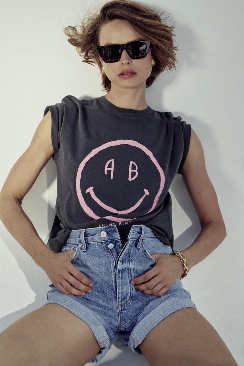 Tee-shirt manches courtes Cade Anine Bing en coton gris d&eacute;lav&eacute; s&eacute;rigraphie rose smiley &laquo; AB &raquo; sur le devant, port&eacute; de face avec les manches roulott&eacute;es.