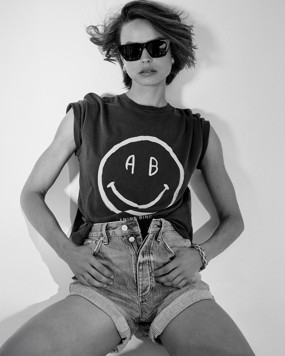 Tee-shirt manches courtes Cade Anine Bing en coton gris d&eacute;lav&eacute; s&eacute;rigraphie rose smiley &laquo; AB &raquo; sur le devant, port&eacute; de face avec un short en denim.