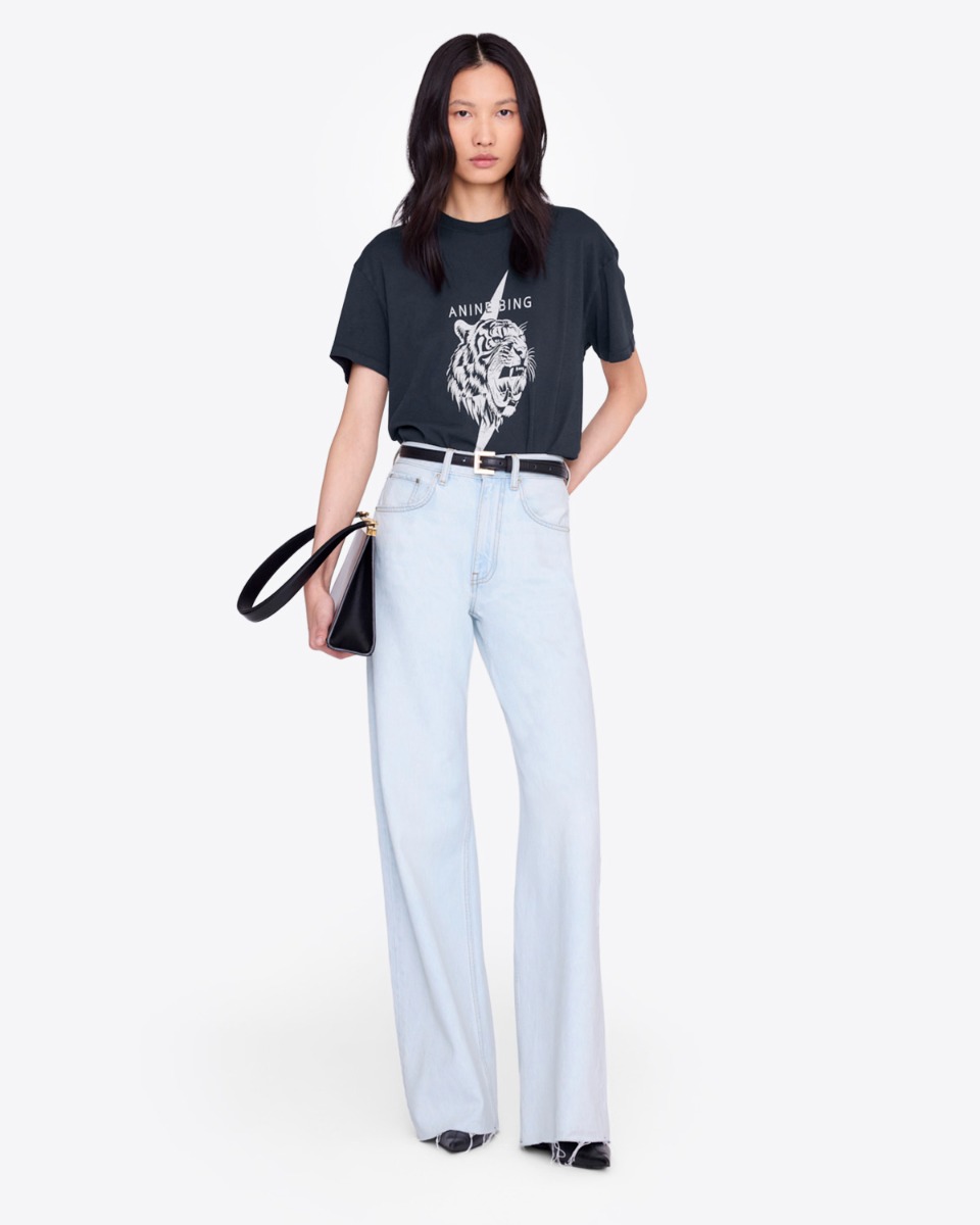 T-shirt Wagner Tiger Anine Bing en coton noir s&eacute;rigraphie tigre blanc devant logo &laquo; ANINE BING &raquo;, port&eacute; de face avec un jean bleu clair.