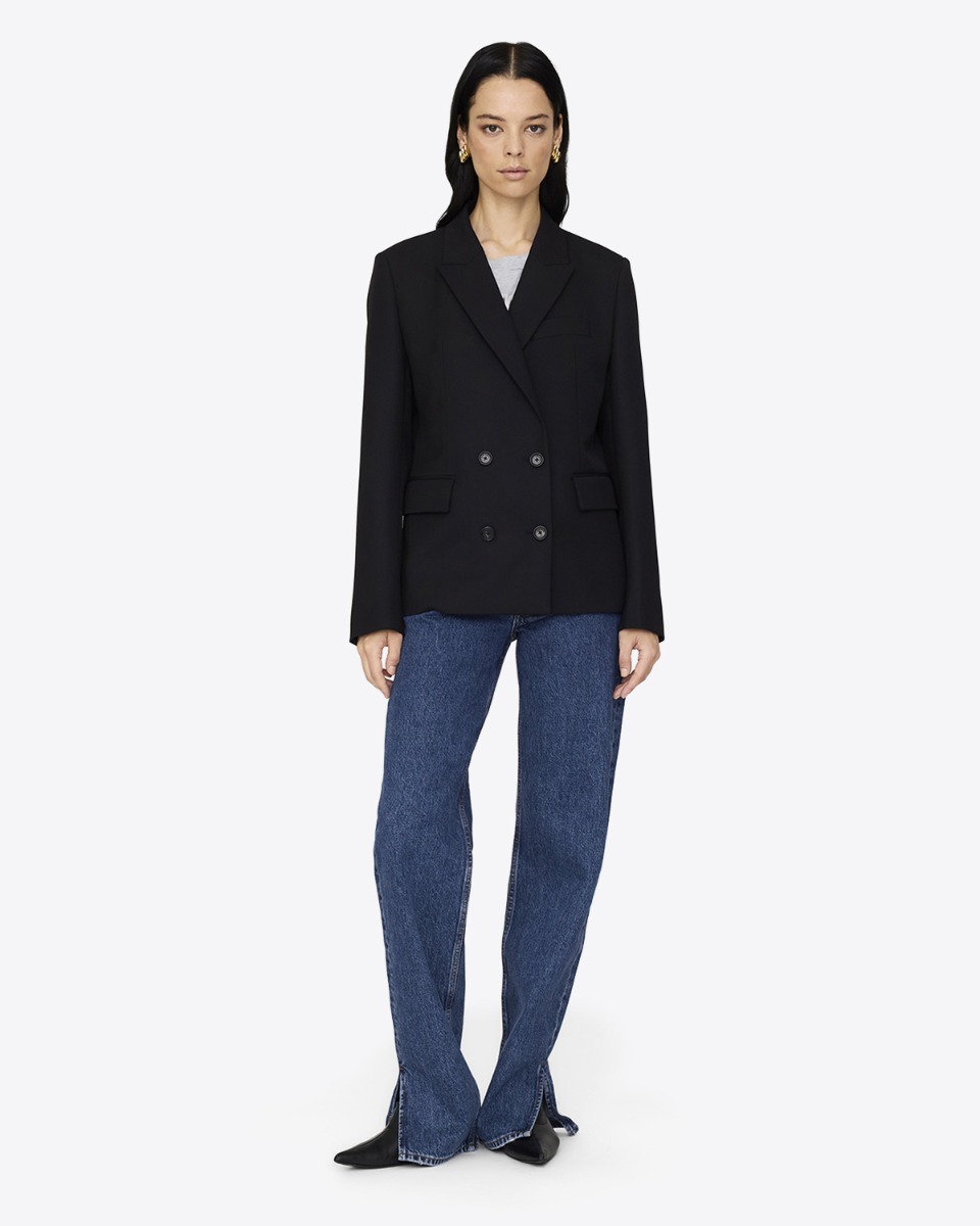 Veste croisée Evalyn Anine Bing noire portée de face fermée avec un jean bleu.