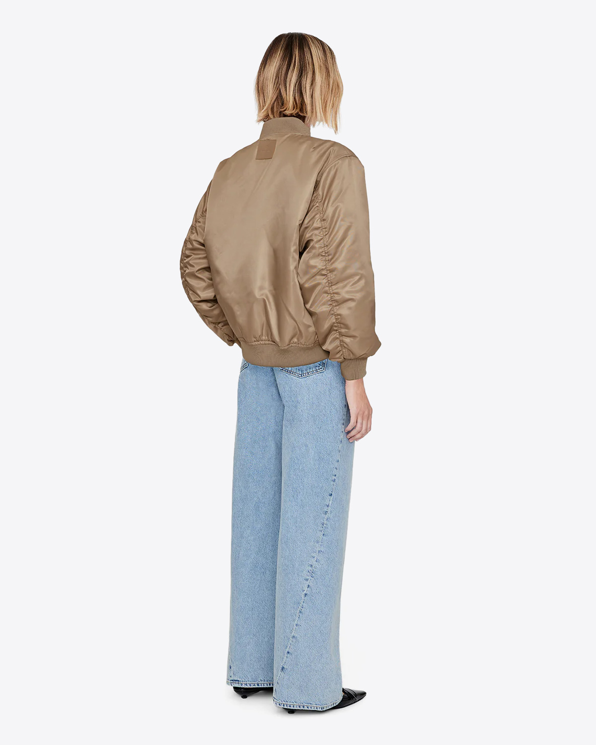 Blouson en nylon beige doré Sépia Léon Anine Bing. Porté de dos avec un jean bleu ciel.
