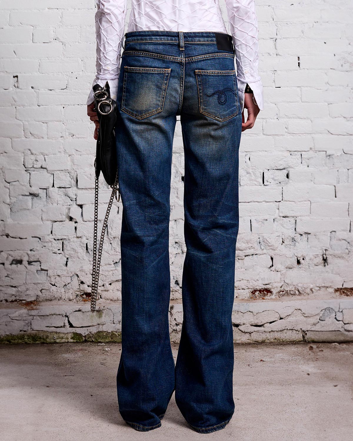 Jean Boy Flare taille basse évasé bleu délavé r13. Porté avec une pochette noire. 