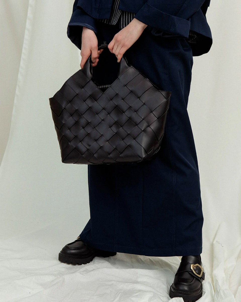 Sac Misu Large Cala Jade en cuir tress&eacute; noir, port&eacute; de face &agrave; la main.