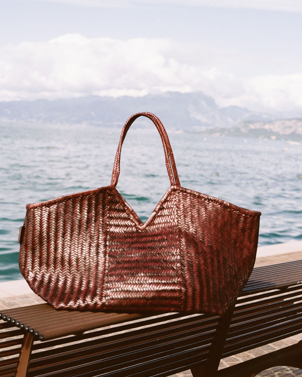 Sac Humi XL Cala Jade en cuir tressé Fudge, posé sur une table.