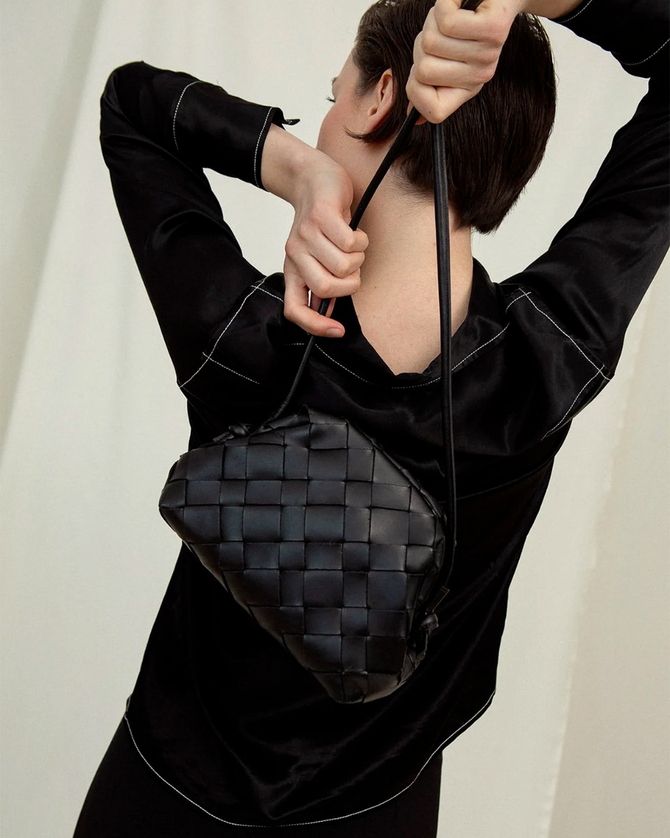 Sac pochette Aimee Cala Jade en cuir tress&eacute; noir. D&eacute;tail de la bandouli&egrave;re longue.