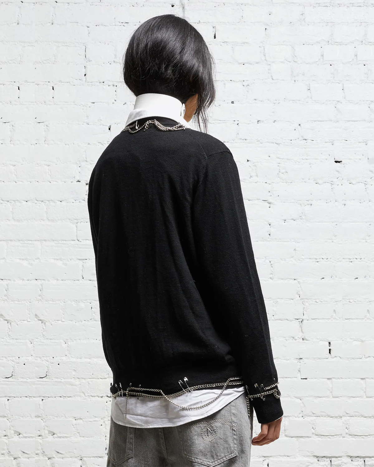 Cardigan noir avec chaines et épingles à nourrices R13 Denim. Porté profil dos. 