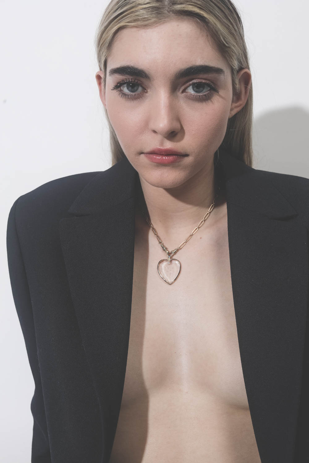 Collier ras de cou en or avec pendentif coeur en cristal Gabin N°2 Pascale Monvoisin. Porté avec une veste noire.