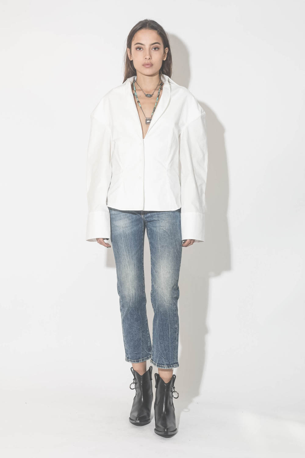 Collier oeil saphir sur cordon tressé en fil de soie métallique Patricia Arango. Porté avec une chemise blanche et un jeans. 
