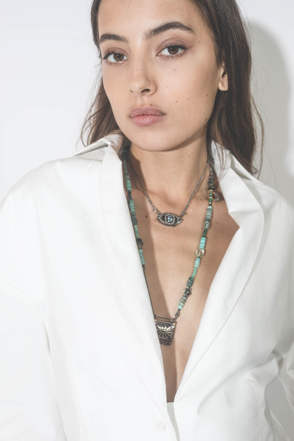 Collier oeil saphir sur cordon tressé en fil de soie métallique Patricia Arango. Porté avec un sautoir.