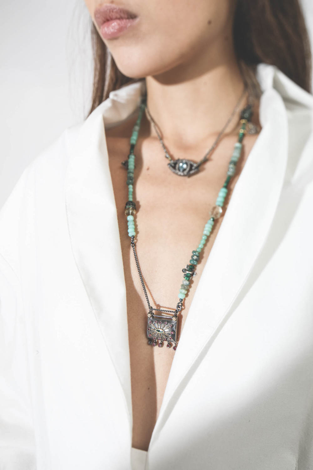 Collier oeil saphir sur cordon tressé en fil de soie métallique Patricia Arango. Porté en accumulation.