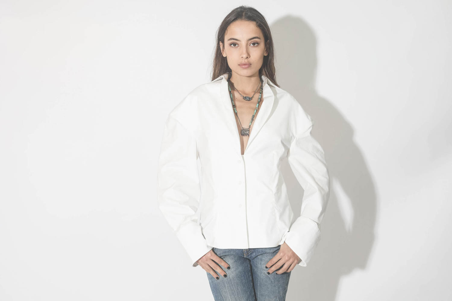 Collier oeil saphir sur cordon tressé en fil de soie métallique Patricia Arango. Porté avec une blouse blanche.