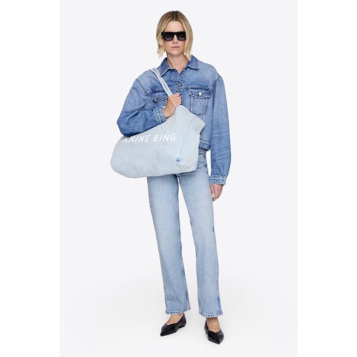 Cabas Leo Anine Bing en toile denim bleu clair et logo « ANINE BING » sur le devant, porté à l'épaule.