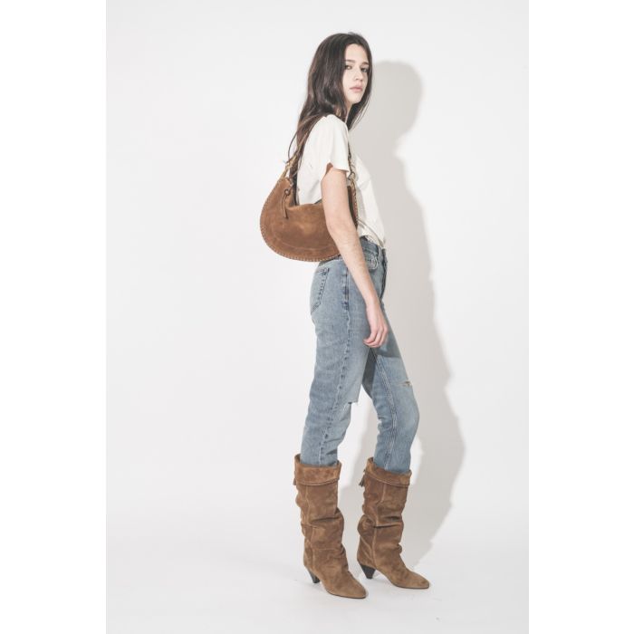 Jean taille haute slim Bruno Anine Bing en denim régénératif bleu déchiré aux genoux, porté de profil.
