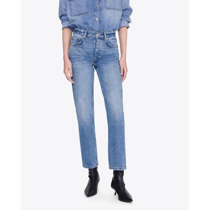 Jean taille haute ajusté Jane Anine Bing en denim bleu ciel délavage Cascade Blue, porté de face avec des boots en cuir noir.