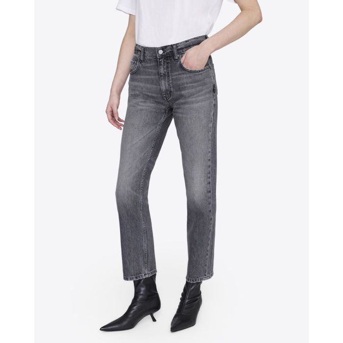 Jean taille haute Kate Anine Bing en denim gris délavé, porté de face avec des boots en cuir noir.