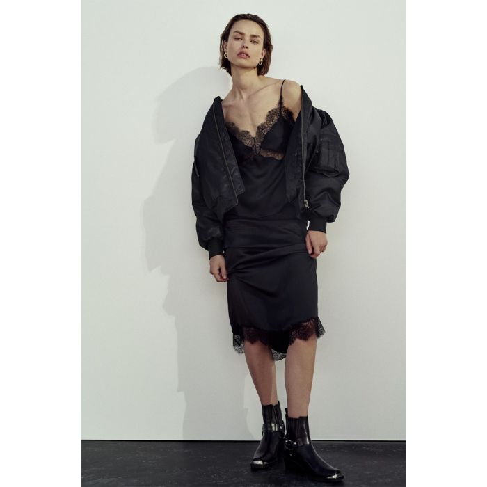 Jupe longue Shelby noire Anine Bing en satin et dentelle esprit lingerie portée avec un bombardier noir.