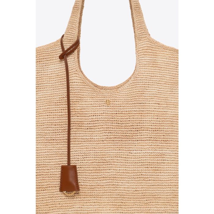 Sac cabas Lili Tote Anine Bing en raphia naturel. Détail du mini-logo « AB » doré sur le devant et du lien porte-clefs en cuir marron.