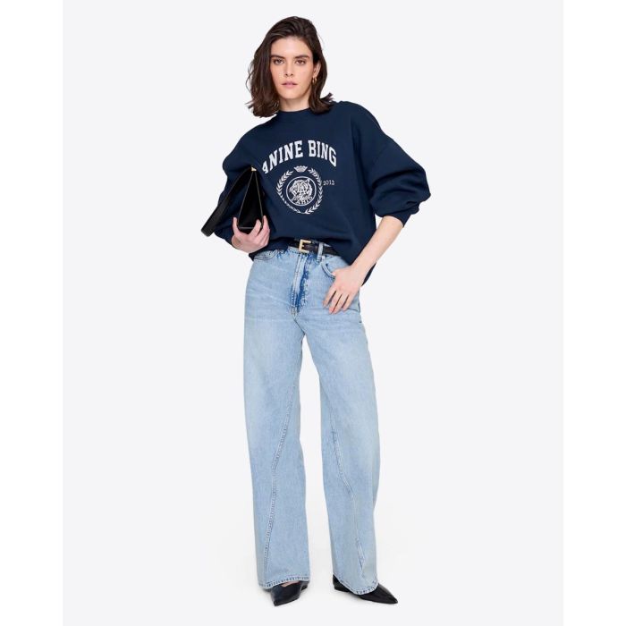 Sweatshirt Miles Collegiate Anine Bing en coton vintage black, sérigraphie blanche brodée collège sur le devant, porté de face légèrement rentré dans le jean.