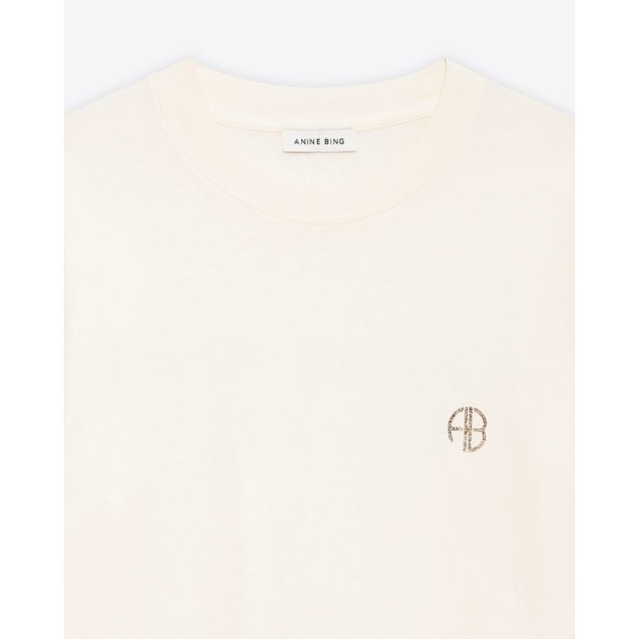 Tee-shirt manches courtes Wagner Soft Stencil Anine Bing en coton crème, logo AB poitrine, sérigraphie dans le dos. Détail du col bord-côte et du logo AB poitrine.