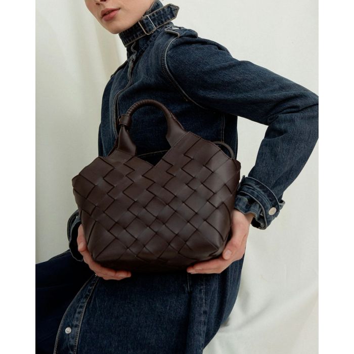 Sac Misu Cala Jade en cuir tressé noir, porté à la main. 