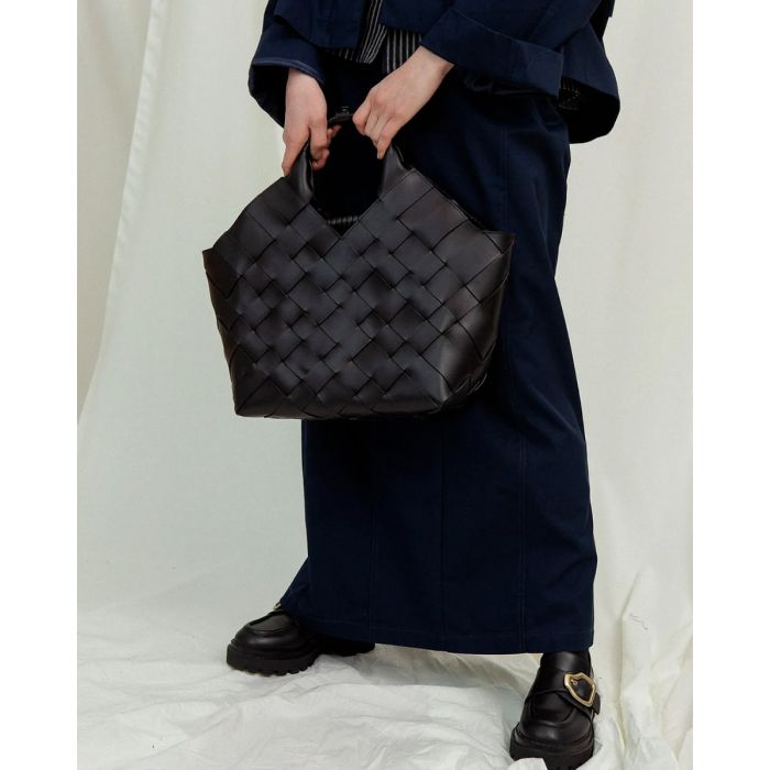 Sac Misu Large Cala Jade en cuir tressé noir, porté de face à la main.