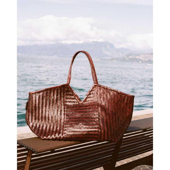 Sac Humi XL Cala Jade en cuir tressé Fudge, posé sur une table.