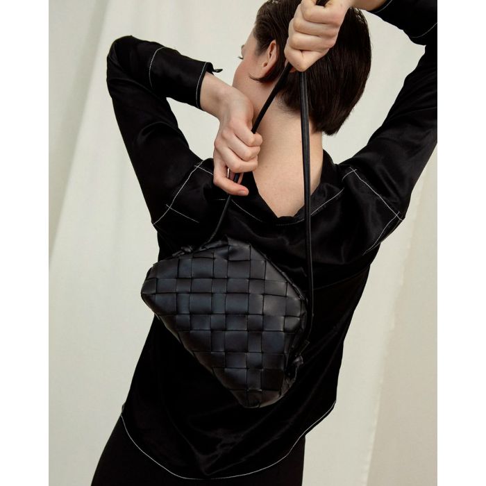 Sac pochette Aimee Cala Jade en cuir tressé noir. Détail de la bandoulière longue.