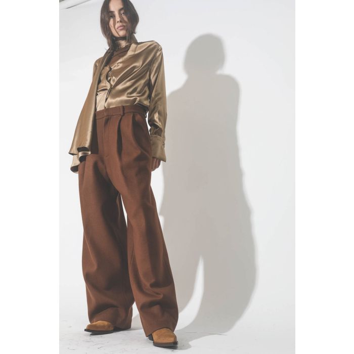 Chemise manches longues drapée col écharpe en satin de soie camel doré. Porté avec un pantalon à pinces marron et des boots santiags camel.