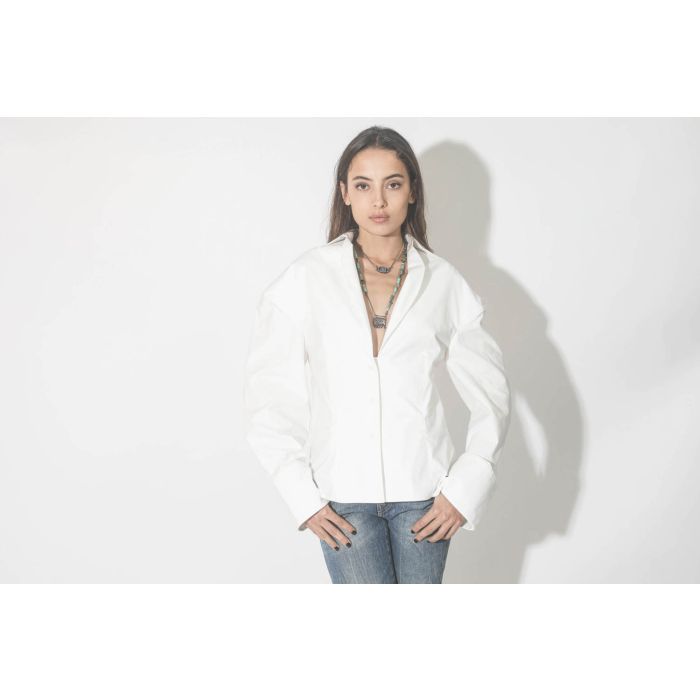 Collier oeil saphir sur cordon tressé en fil de soie métallique Patricia Arango. Porté avec une blouse blanche.