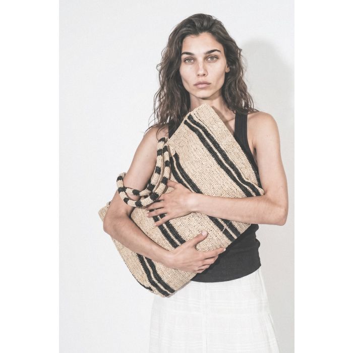 Grand Cabas Raffia Weekender Vacation Road Gabriele Frantzen en raphia rayé écru et noir, porté dans les bras.