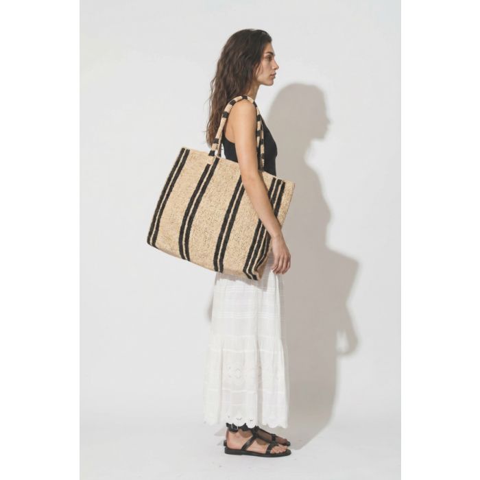 Grand Cabas Raffia Weekender Vacation Road Gabriele Frantzen en raphia rayé écru et noir, porté de profil à l'épaule.