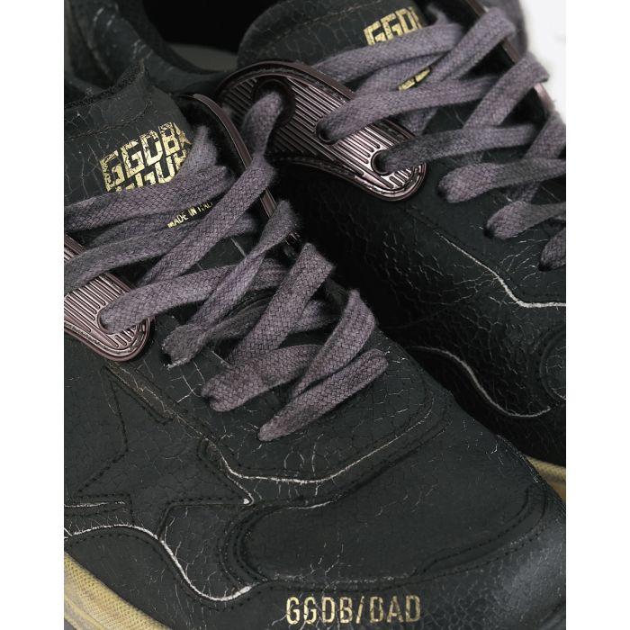 Sneakers Running Dad Golden Goose en cuir craquelé noir, étoile noire, semelle dorée. Détails des lacets noirs et du cuir craquelé.