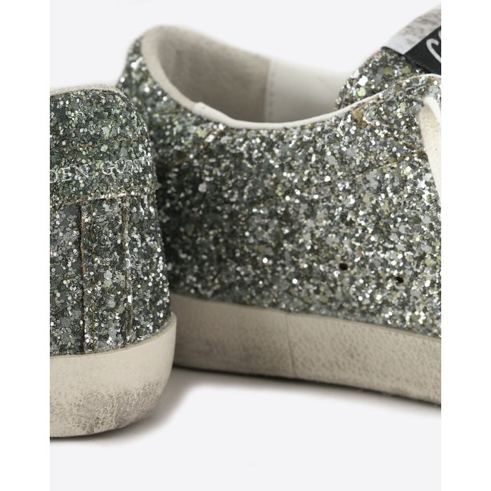 Sneakers Superstar Golden Goose femme à paillettes argentées avec des reflets verts, étoile en cuir lisse doré. Détail du renfort à paillettes.