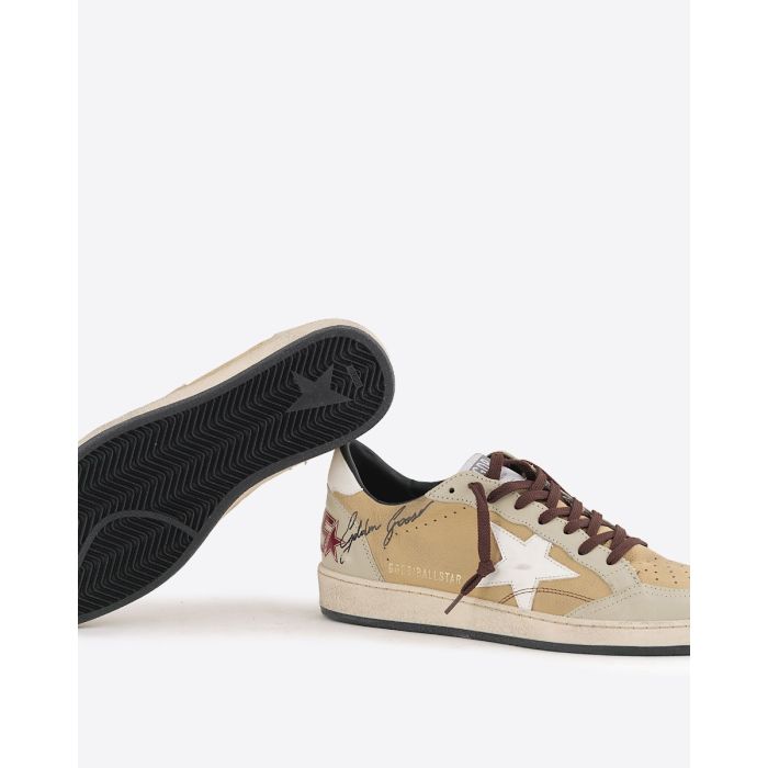Sneakers Ball Star Golden Goose homme en cuir beige, empiècement écru, étoile blanche arrière blanc. Signature volontairement usé "Golden Goose" effet graffiti sur le côté. Lacets bordeaux. Détail de la semelle noire.